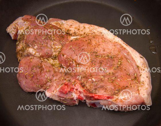 Fresh raw pork steak with spices roasting on frying pan