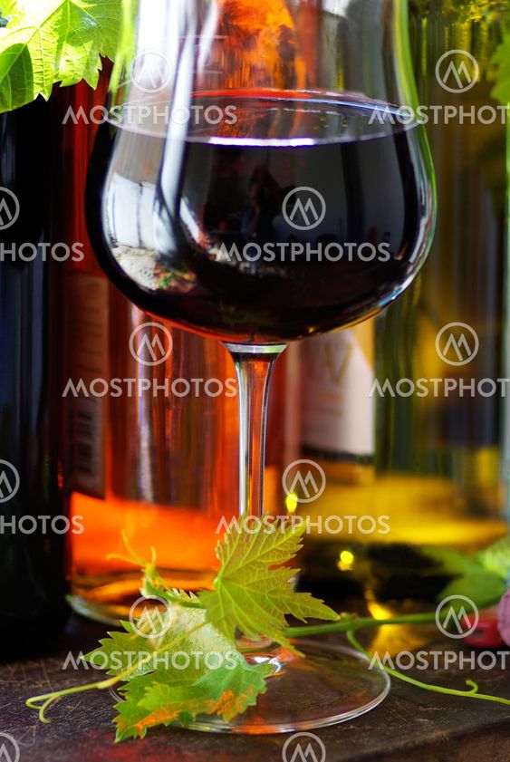 Bottle of red wine with glassand leaves.