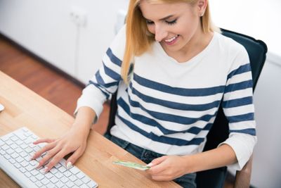 Woman holding bank card and typing on keyboard