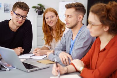 Smiling woman with coworkers around laptop at work