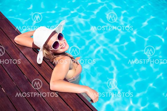 Beautiful woman wearing sunglasses and straw hat leaning...