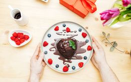 The hands of a man hold a plate with a heart-shaped...