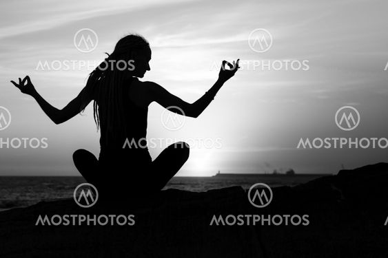 Black-and-white silhouette of yoga woman meditation on the sea beach.