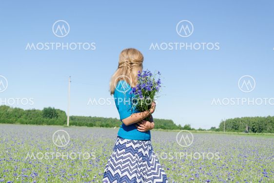 girl with bluet bouquet in wide meadow back view
