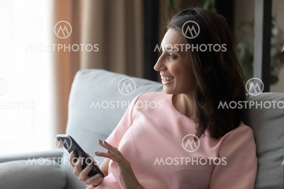 Close up smiling Arabian woman distracted from phone at...