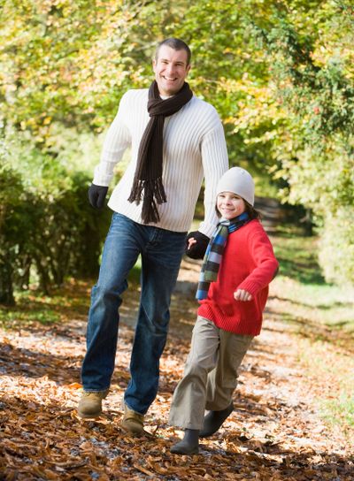 Father and son running along autumn path