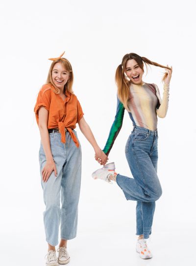 Full length photo of two adorable girls wearing colorful...