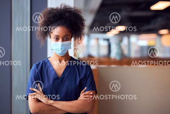 Female Doctor In Face Mask Wearing Scrubs Under Pressure...