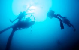 group of divers scuba diving in a wreck at ocean