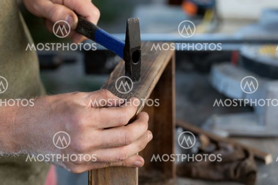 carpenters are preparing to hammer nail into wooden product