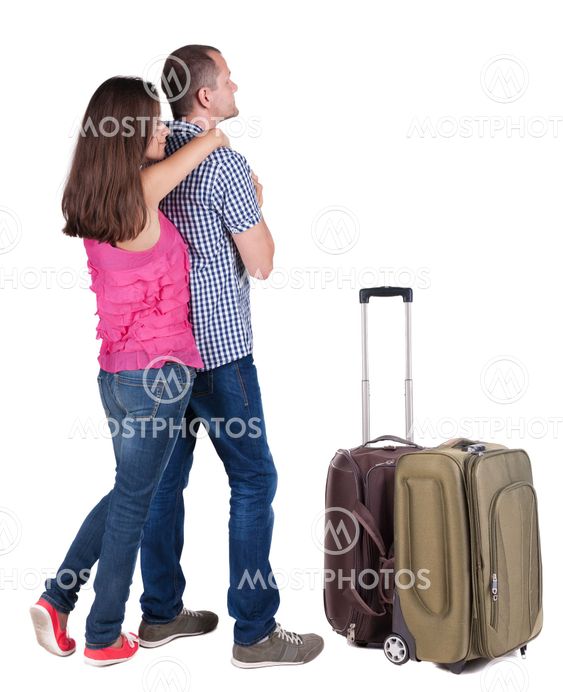 Back view of young couple traveling with suitcas .