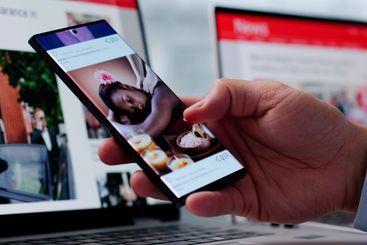 Watching Online News Article On Mobile Phone And Laptop