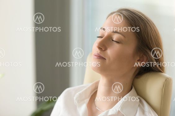 Businesswoman lying on back chair with closed eyes