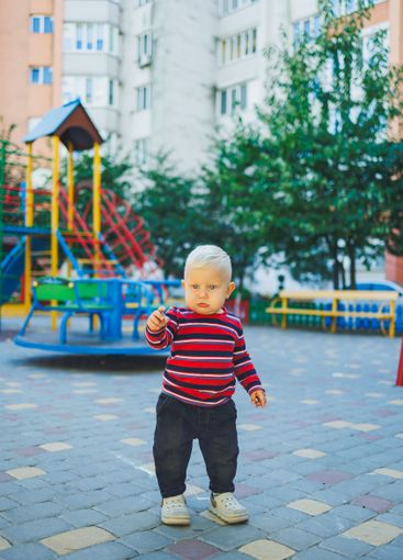 A fair-haired one-year-old boy in jeans and sneakers...
