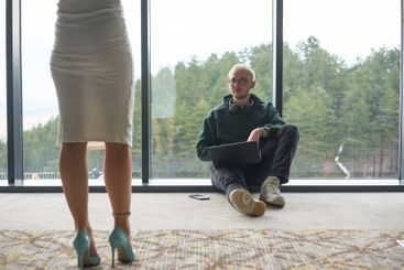 A blonde man sitting casually on the floor of a modern...