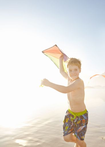 Ocean, boy and running with kite for playing, childhood...
