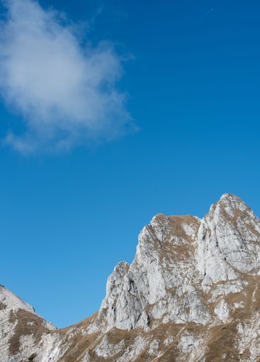 Rocky mountain peaks touching blue sky with cloudscape...