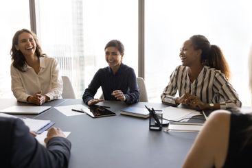 Indian, African and Caucasian workmates laughing during...