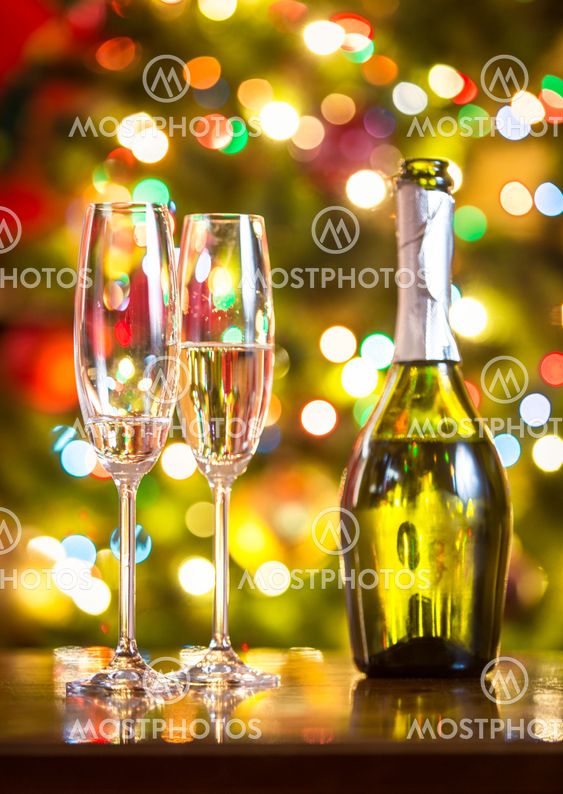 champagne flutes and bottle on table against Christmas...