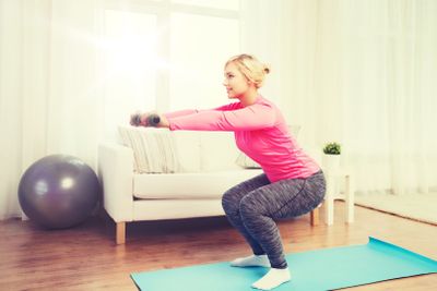 smiling woman with dumbbells exercising at home