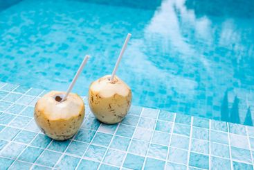 A fresh coconuts with a straw lies on the side of the...