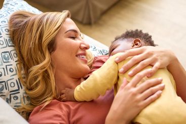Overhead Shot Of Loving Mother Cuddling Baby Daughter...