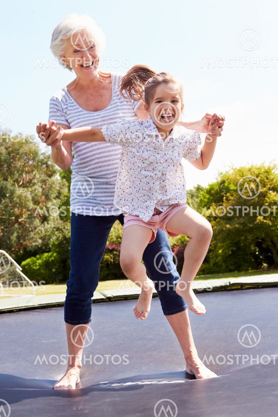 Grandmother And Granddaughter Bouncing On Trampoline