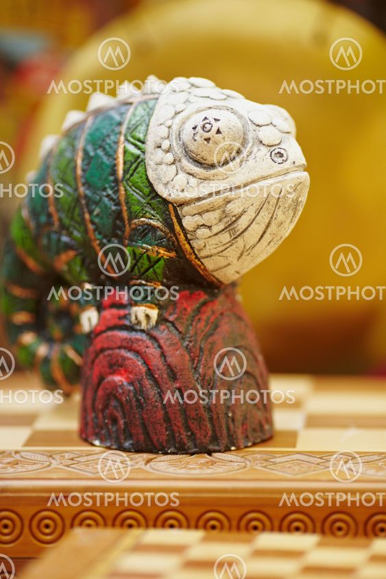 Figurine of chameleon on a chess-board.