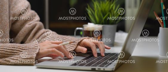 Female typing on laptop on office desk with a cup of...
