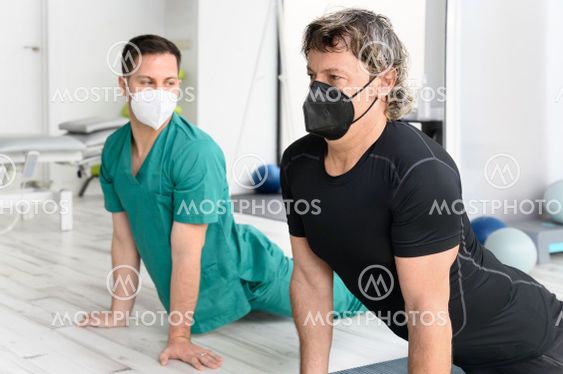Therapist with protective face mask Assisting patient...