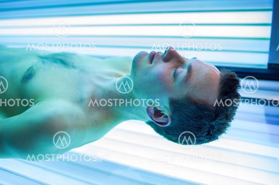 Handsome young man relaxing during a tanning session in a modern solarium