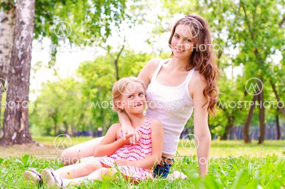 mother and daughter sitting together on the grass