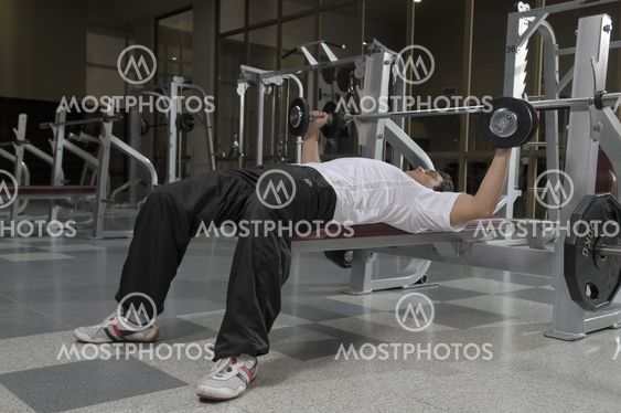 Man wearing a white t-shirt doing weights at gym
