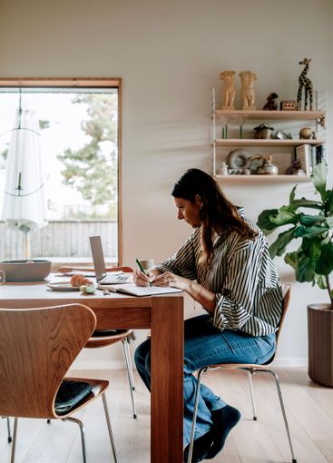 Focused female freelancer working while sitting near...