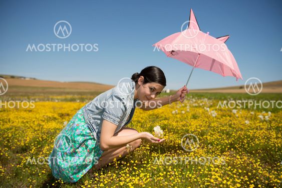 Beautiful adult smelling flowers on sunny field enjoying herself