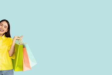 Emotional young brunette woman holding bright shopping bags