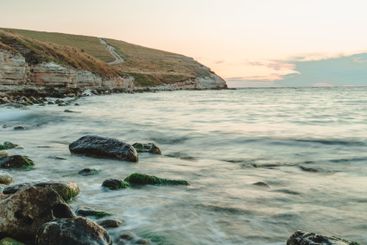 Coastal sunset view with gentle waves and rocky...