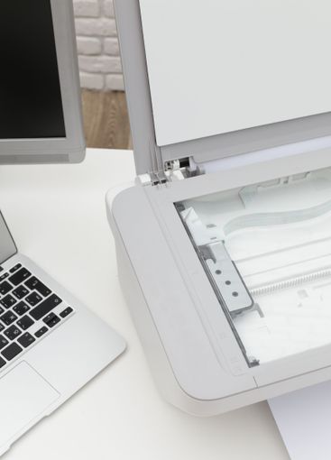 Office workspace showing a scanner with a laptop and a...