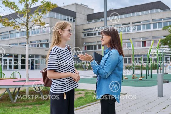 Talking teacher and teenage schoolgirl outdoor, school...