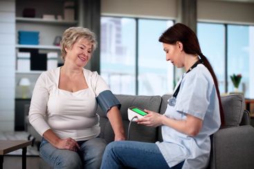 Happy Female Doctor Measuring Senior Patient Blood...