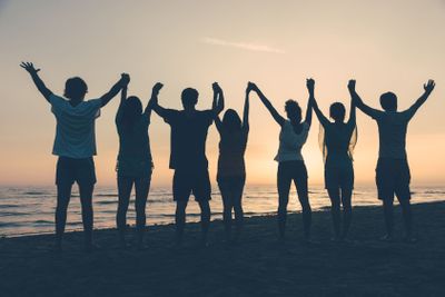 Group of People with Raised Arms looking at Sunset