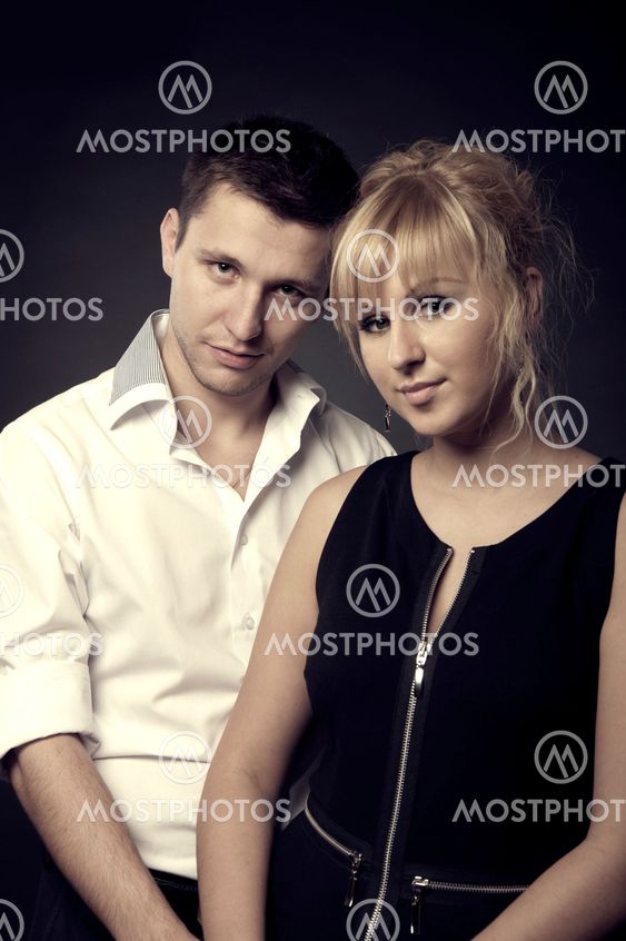 close up portrait of a young couple together on black background