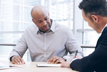 Businessmen, writing or signing with contract for...