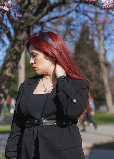 Red haired woman wearing stylish outfit near blossoming...
