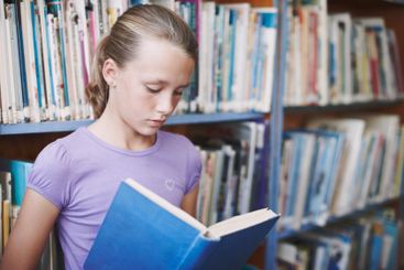 Girl, library and concentration for reading book at...