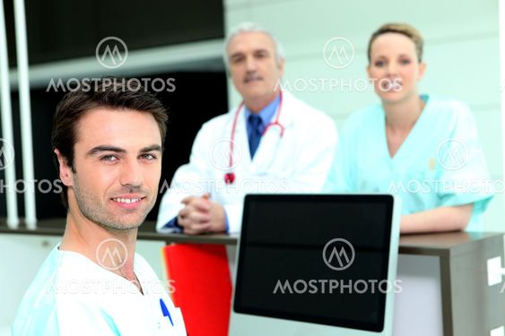 Doctor and nurses around a computer with a blank screen