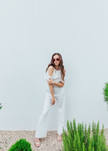 Beautiful brunette woman in white suit posing by the...