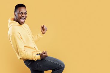 Emotional Black Man Shaking Fists In Joy Over Yellow...