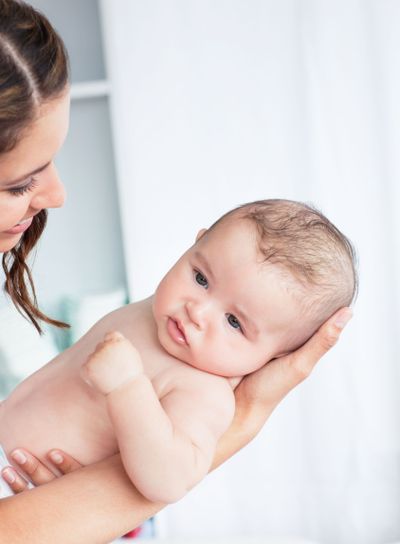 Portrait of a careful mother holding her baby after the...
