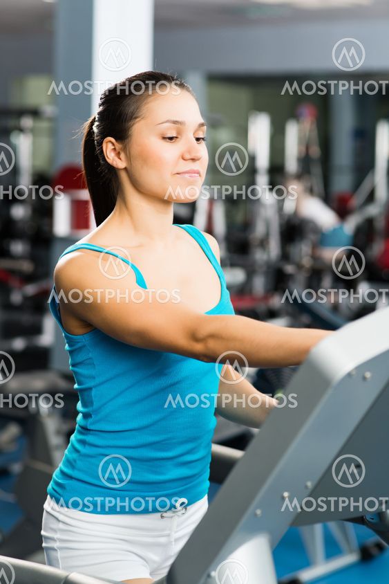 attractive young woman adjusts the treadmill